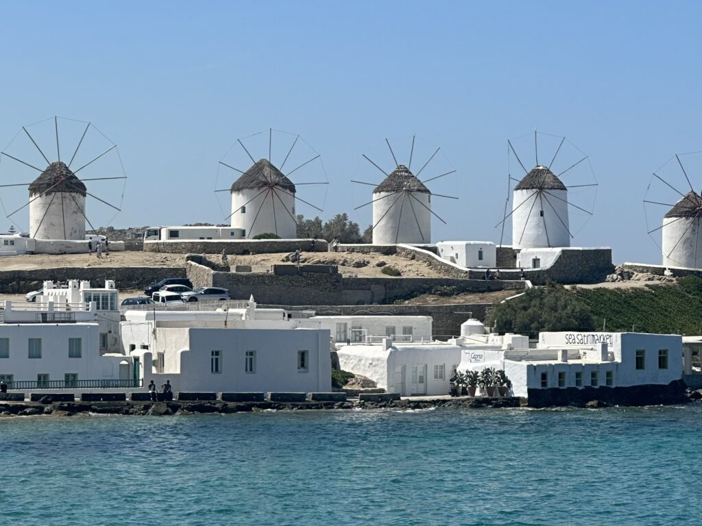 Mykonos Town windmills at sunset with Little Venice waterfront in the foreground