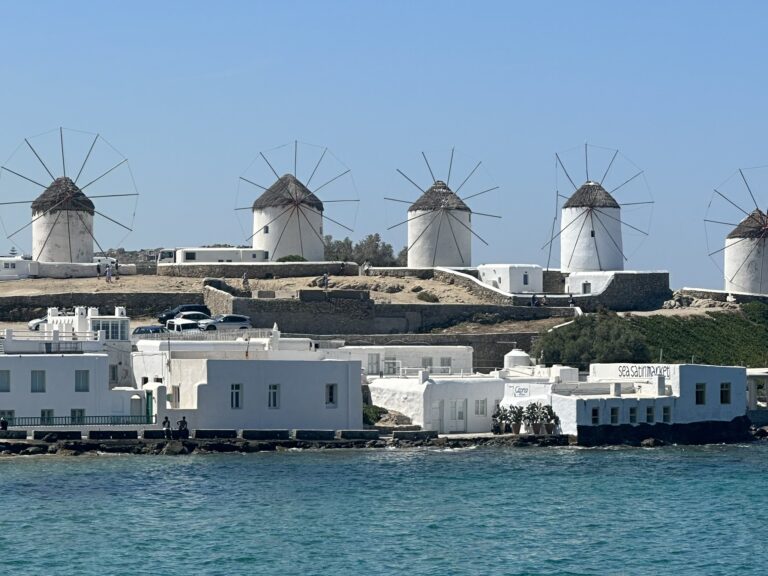 Mykonos Town windmills at sunset with Little Venice waterfront in the foreground